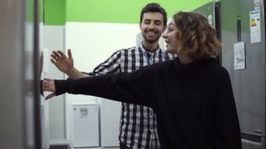 Genç bir kadın, tüketici elektroniği mağazasından almadan önce erkek danışmanla tasarım ve kaliteyi tartışıyor. Mağaza danışmanıyla özellikler tartışılıyor