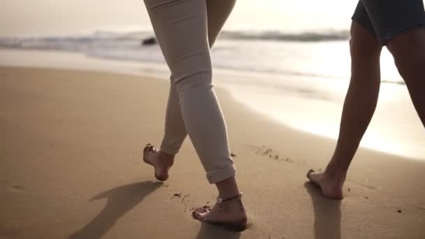 Niedriger Abschnitt eines Paares, das barfuß am Strand spaziert.Sie verbringen Zeit miteinander und hinterlassen Spuren auf nassem Sand — Stockvideo