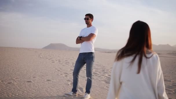 Primer plano escena de beso sensual de teo younf hombre en mujer en gafas de sol contra la luz del sol en desierto arenoso. Hombre de pie esperando a su novia, acariciando su pelo y beso — Vídeo de stock