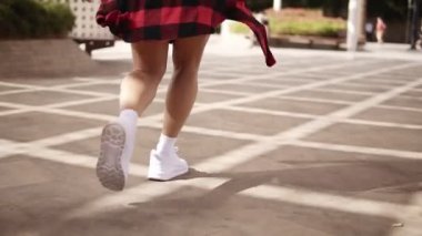 Güneş gözlüklü uzun saçlı neşeli genç kadın tropikal parkta yürüyor. Neşeli, gülümseyen kız yürüyor, arkasını dönüyor ve kameraya gülümsüyor. Ağır çekim. Aşağıdan