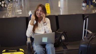 Şık, beyaz gömlekli güzel kız kalkış salonunda beklerken havaalanında telefon ve dizüstü bilgisayar kullanıyor. Arkadaşlarıyla konuşuyor, gülümsüyor ve heyecanlanıyor. Pasaport elinde.