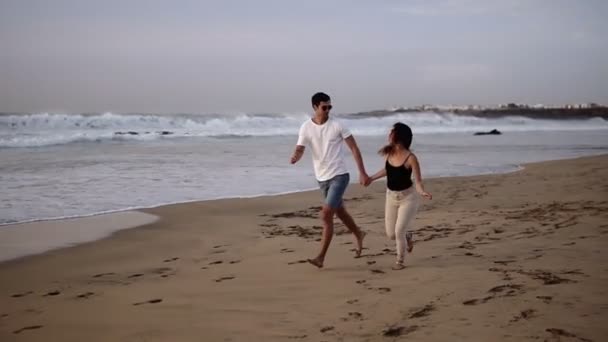 Perfect scene. Couple enjoy summer vacation on the large beach, enjoy life and running in scenery slow motion video on background ocean landscape. Young couple running into tropical ocean, happy smile — Stock Video