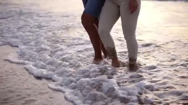 Close-up ver vídeo de homem e mulher andando descalços na praia de areia pelo oceano. Casal feliz desfrutando de férias de verão em país quente. Filmagem em câmara lenta, ondas de espuma — Vídeo de Stock