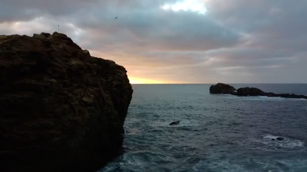 Ranní soumrak. Mořské vlny, hektický oceán. Letecké záběry, vlny narážející do skal. Slunce vychází na obzoru, za kopci na pozadí — Stock video