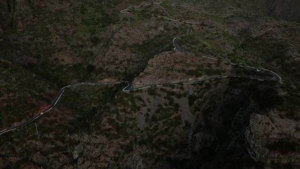 Vista aérea sobre una carretera serpantina con coches. Vuelo aéreo sobre serpentina carretera más allá de las montañas cubiertas de arbustos verdes y marrones. Coches conduciendo, cámara lenta — Vídeos de Stock