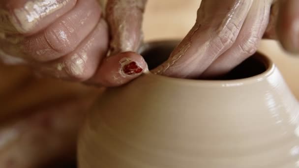Umiejętne, mokre kobiece ręce garncarza kształtujące glinę na kole garncarskim i rzeźbiące wazon palcami. Produkcja tradycyjnego wazonu w kształcie. Zamknij się. — Wideo stockowe