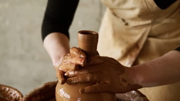 Las mujeres alfareras manos con manicura roja trabajando con arcilla húmeda en una rueda de cerámica haciendo un producto de arcilla en un taller. Persona femenina irreconocible formando un jarrón, tira hacia arriba el cuello — Vídeo de stock