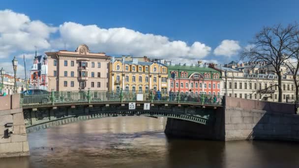 Zobacz do pierwszej inżynier most nad rzeką Moyka czerwone i żółte Olsufiev's domy w tle. Słoneczny dzień, niebieski niebo z chmur cumulus. Saint-Petersburg, Federacja Rosyjska. Upływ czasu. — Wideo stockowe