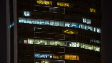 Geceleri çalışan insanlar içinde ofis windows gökdelenin şehir görünümüne kadar kapatın. Dubai, Birleşik Arap Emirlikleri