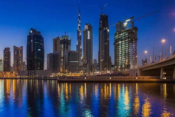 Gün batımı iş koy ve şehir üzerinde alan Dubai, Dubai creek içinde gökdelenler gece aydınlatma yansıması.
