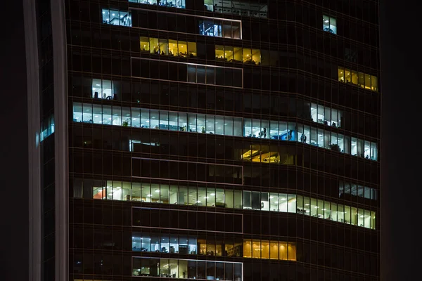 Geceleri çalışan insanlar içinde ofis windows gökdelenin şehir görünümüne kadar kapatın. Dubai, Birleşik Arap Emirlikleri