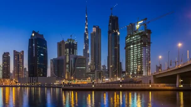 Sonnenuntergang über der Businessbucht und der Innenstadt von Dubai, Reflexion der nächtlichen Illumination von Wolkenkratzern im Dubai Creek. — Stockvideo