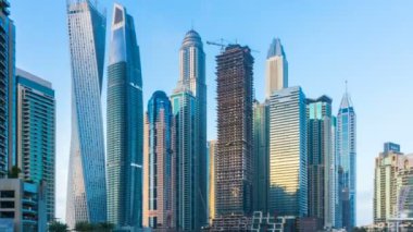 Dubai Yat Limanı en yüksek modern kuleleri ve gün batımında kayan yat ve tekne timelapse gezinti güzel manzarasının.