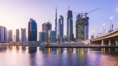 Gün batımı iş koy ve şehir üzerinde alan Dubai, Dubai creek içinde gökdelenler gece aydınlatma yansıması.