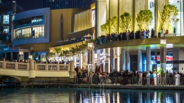 Timelapse del Dubai Mall con iluminación nocturna. Gente viendo un espectáculo de fuentes cerca del centro comercial. Dubai, Emiratos Árabes Unidos — Vídeos de Stock
