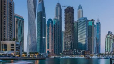 Dubai Yat Limanı en yüksek modern kuleleri ve gün batımında kayan yat ve tekne timelapse gezinti güzel manzarasının.