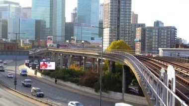 Tren Doğu Hindistan istasyonuna yaklaşıyor. Docklands Light Railway, Aspen Yolu 'nda araba trafiği, arka planda Canary Wharf gökdelenleri. Londra, Uk.