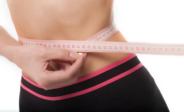 Женщина измеряет свое стройное тело на белом фоне. Концепция здоровья . — стоковое фото