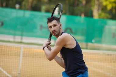 Mutlu genç adam Tenis kil sahada oynayan.