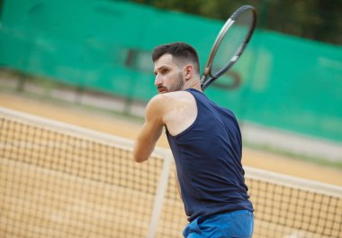 Mutlu genç adam Tenis kil sahada oynayan.
