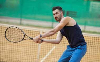 Mutlu genç adam Tenis kil sahada oynayan.