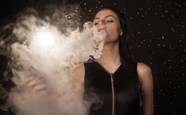Genç güzel kadın vaping e-sigara. Kadının yüzündeki akan su.
