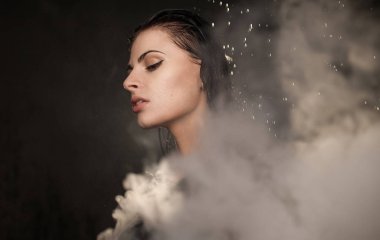 Genç güzel kadın vaping e-sigara. Kadının yüzündeki akan su.