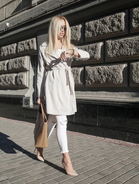 Joven mujer de negocios comprueba el tiempo en su reloj de pulsera de pie en la calle —  Fotos de Stock