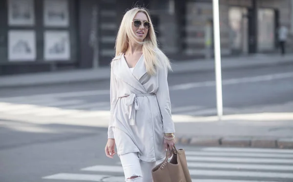 Kvinnligt mode - urban stil. Unga attraktiva trendiga kvinnan modell poserar utomhus med väska i handen. — Stockfoto