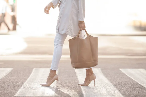 Piernas de mujer en zapatos de moda y bolsa en la mano — Foto de Stock