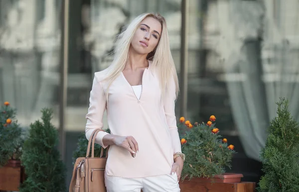 Kvinnligt mode - urban stil. Unga attraktiva trendiga kvinnan modell poserar utomhus med väska i handen. — Stockfoto