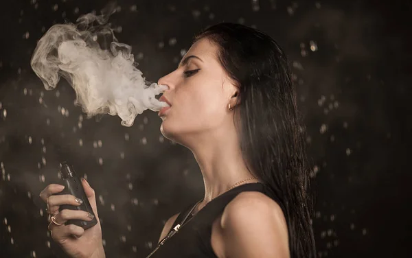 Joven hermosa mujer vapeando cigarrillo electrónico. Agua que fluye en la cara mujer . — Foto de Stock