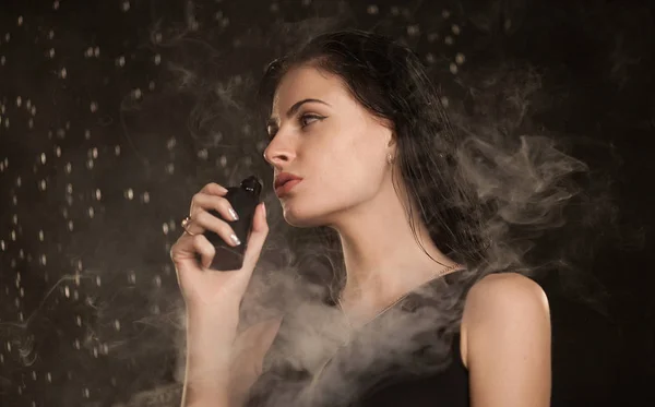 Joven hermosa mujer vapeando cigarrillo electrónico. Agua que fluye en la cara mujer . — Foto de Stock