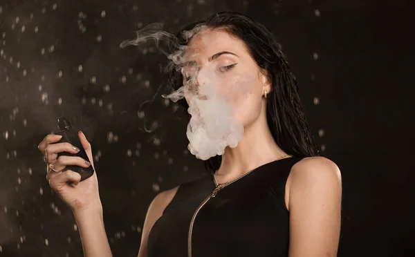 Молода красива жінка пара електронна сигарета. Вода тече на обличчі жінки . — стокове фото