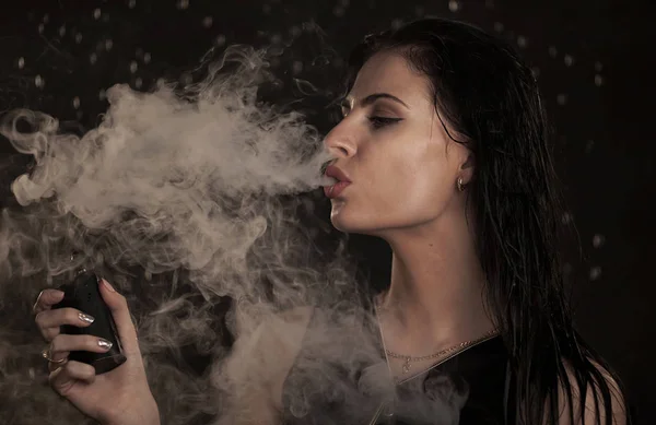 Joven hermosa mujer vapeando cigarrillo electrónico. Agua que fluye en la cara mujer . — Foto de Stock