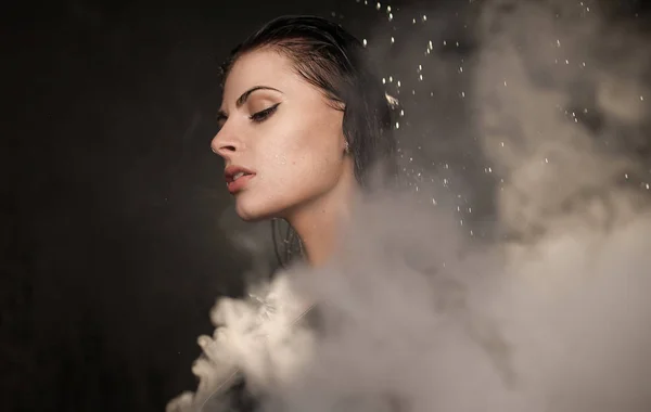 Joven hermosa mujer vapeando cigarrillo electrónico. Agua que fluye en la cara mujer . — Foto de Stock