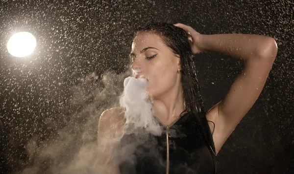 Junge schöne Frau, die E-Zigarette dampft. Wasser fließt auf das Gesicht der Frau. — Stockfoto