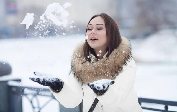 Boldog a gyönyörű fiatal nő fúj hópelyhek a kezét egy téli napon — Stock Fotó