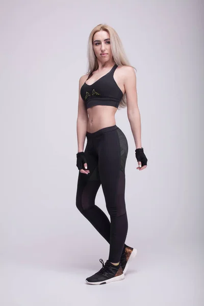 Mooie jongedame in fitness dragen over grijze achtergrond — Stockfoto