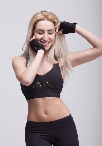 Mujer hermosa joven en ropa de fitness sobre fondo gris — Foto de Stock