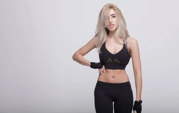 Ung vacker kvinna i fitness slitas med grå bakgrund — Stockfoto