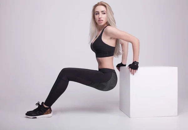 Joven positivo fitness mujer rubia de entrenamiento con cubo blanco. Mujer delgada en ropa deportiva . — Foto de Stock