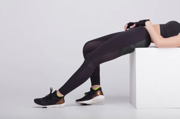 Close-up van sexy zijaanzicht van de benen van de vrouw rekken van de spieren van de voet in grijze sport thermisch ondergoed met patroon op grijze achtergrond. — Stockfoto