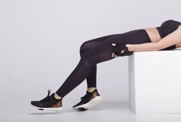 Stäng upp sexiga sidovy av kvinna ben stretching musklerna i foten i grå sport Termisk underkläder med mönster på grå bakgrund. — Stockfoto
