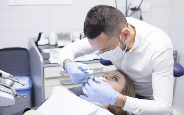 El dentista trata a una paciente con dientes en el consultorio del hospital —  Fotos de Stock