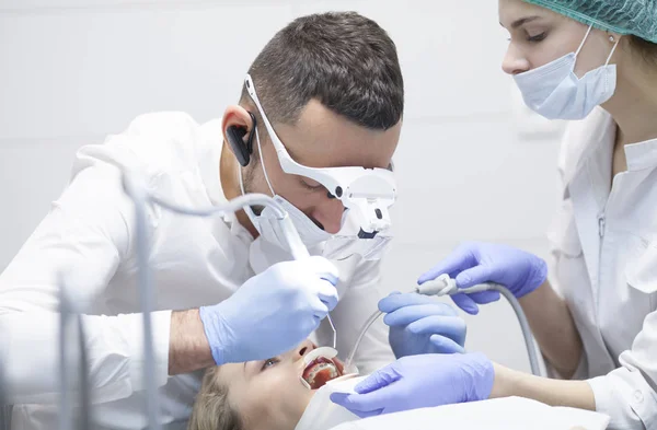 El dentista trata a una paciente con dientes en el consultorio del hospital —  Fotos de Stock