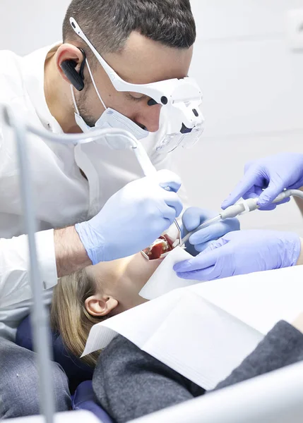 Doktor zubař léčí zuby krásné mladé dívky pacienta. Ta dívka na recepci u zubaře. Zubař ošetřuje zub. — Stock fotografie