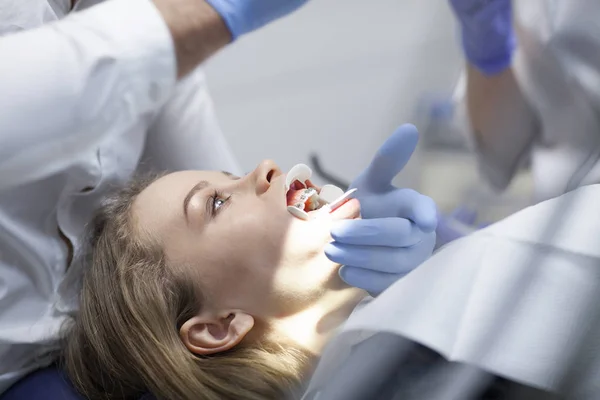 Γιατρός οδοντίατρος αντιμετωπίζει τα δόντια ενός όμορφου ασθενή νεαρή κοπέλα. Το κορίτσι στη ρεσεψιόν στον οδοντίατρο. Γιατρός οδοντίατρος αντιμετωπίζει δόντι. — Φωτογραφία Αρχείου