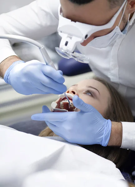 Medico dentista tratta i denti di una bella ragazza paziente. La ragazza alla reception dal dentista. Medico dentista tratta dente. — Foto Stock