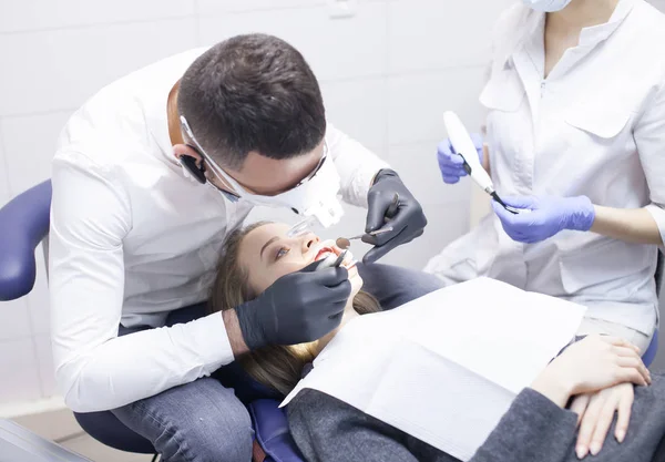 Doctor dentista trata los dientes de una hermosa joven paciente. La chica en recepción en el dentista. Médico dentista trata diente. —  Fotos de Stock